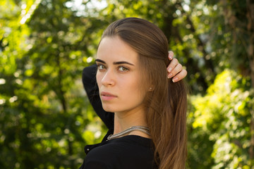 Fototapeta premium Young woman standing back on the background of trees