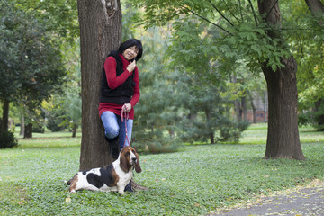 A young woman walking a dog in the park