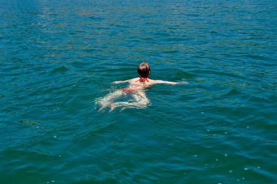 Junge Frau am Schwimmen im t&uuml;rkisblauen See - Brustschwimmen
