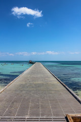 Wooden pier in Higgs Beach, a popular Key West beach in Florida known for snorkeling, tropical turquoise waters and white sand. Infinity and freedom concept.