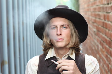 Retro cowboy smoking cigarette. Young man lighting a cigarette