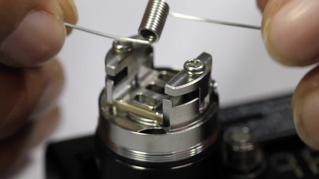 installing a new kanthal micro coil into the atomizer’s deck base of electronic cigarette for vaping by hands and screwdriver, close up scene, high definition, Full HD, 1920x1080