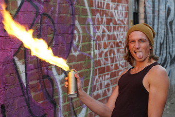 Young male setting spray on fire and sticking his tongue out 