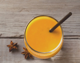 Healthy pumpkin smoothies with spices and nuts on rustic table
