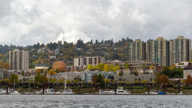Time lapse movie of moving clouds over residential homes and condominiums in downtown Portland Oregon along Willamette River waterfront with boats during colorful fall autumn season 4096x2304