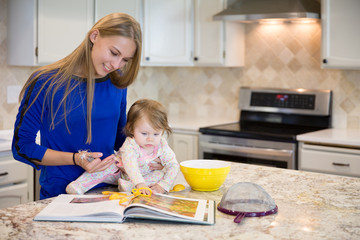 Young beautiful caucasian woman with cute baby girl, kitchen interior