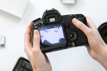 Hands holding a camera, taking a picture of a white desk.