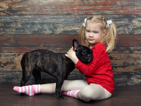 Little girl hugging a dog. Background old wooden board