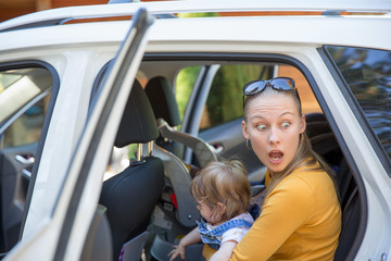 Young woman with surprised look exit the car with baby
