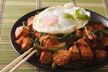 Thai chicken with basil and egg close-up on a plate. horizontal
