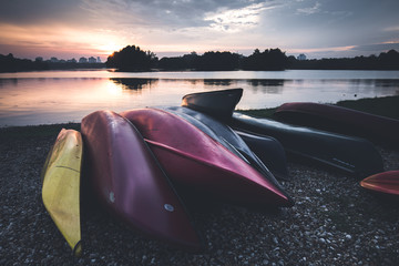 Colorful kayaks shot in landscape format. The sun is just above the tree when the shot is taken.