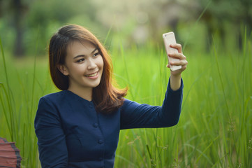 Beautiful Woman are using smartphone in selfie on the fields,vintage style