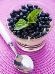 Cream desserts with blueberries and mint in a glass. Vertical sh