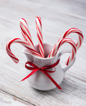 Jug With Christmas Candy Canes On A Wooden Table