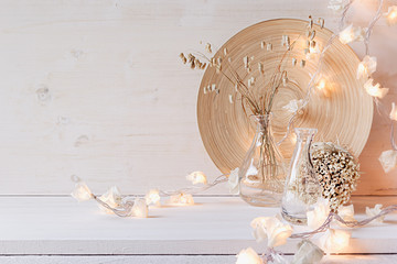 Soft home decor with burning lights on white wooden background. Interior.