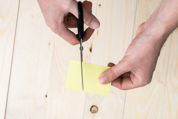 hand is cutting a sheet of yellow paper