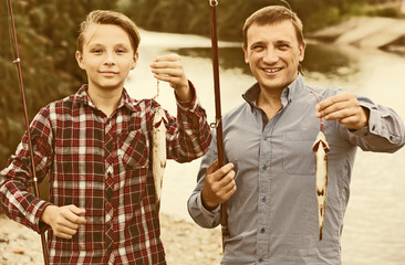 Smiling father with son looking at fish on hook