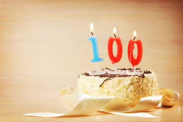 Birthday cake with burning candle as a number one hundred. Focus on the candle