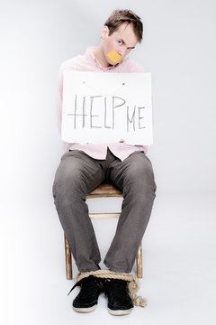 Tied man with taped mouth as a hostage in studio