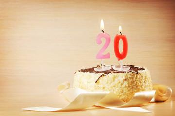 Birthday cake with burning candle as a number twenty. Focus on the candle