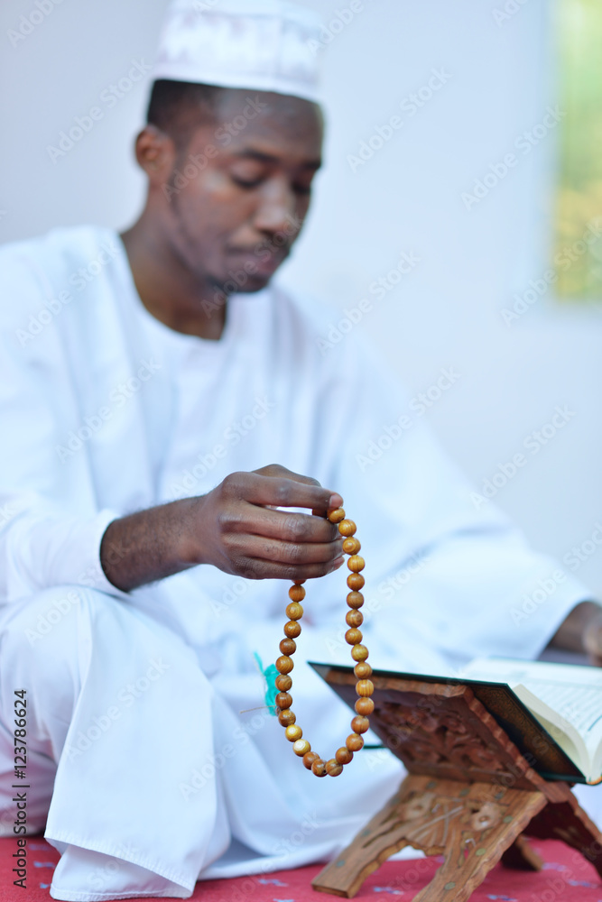 Wall mural African Muslim Man Making Traditional Prayer To God While Wearing A Traditional Cap Dishdash