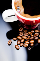 Red cup of coffee with coffee beans and dark background