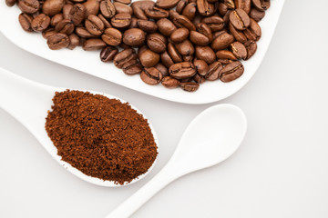 White coffee cup, coffee plate and teaspoon with coffee beans and coffee powder