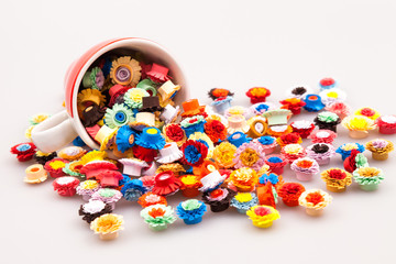 Small, colorful paper flowers made with quilling technique and red coffee cup