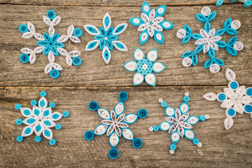 Paper snowflakes made with quilling technique on a wooden surface