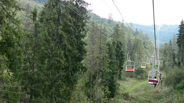 Cableway in the mountains. The girl is carrying a bicycle on top of the mountain.