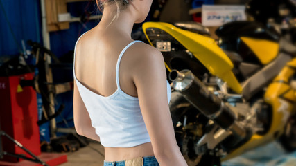 Fototapeta na wymiar Young woman biker girl standing near her motorcycle. Rear view g