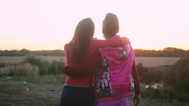 View from the back of mum and daughter watching the sunset hugging on the rock in slowmotion. 1920x1080