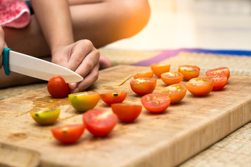 Hands of little girl slicing tomato , prepare for make dinner