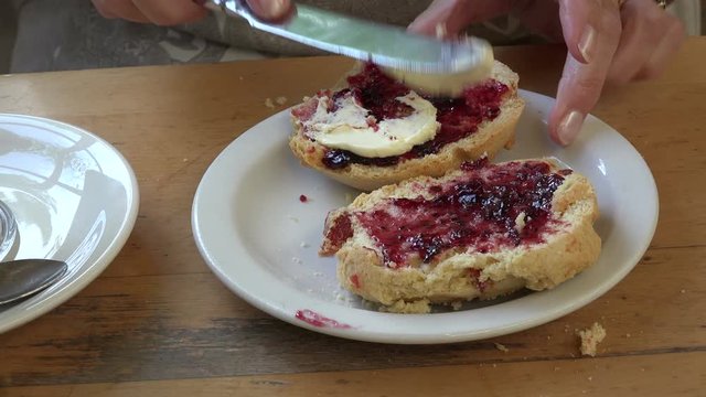 Tilt up of senior woman with coffee cutting scone in cafe