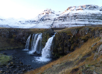 Kirkjufellsfoss waterfall and the snow capped mountain in the morning sunlight, Snaefellsness Peninsula of Iceland