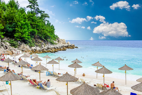 Marble beach (Saliara beach), Thassos Islands, Greece. The most beautiful white beach in Greece. Tourists enjoying a nice day at the beach. Straw umbrellas (straw parasol) and sunbeds on the beach.