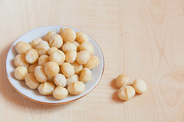 delicious macadamia nuts on  plate on  wooden background