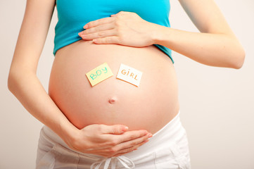 Belly of a young pregnant woman with two stickers isolated on white(boy or girl concept)