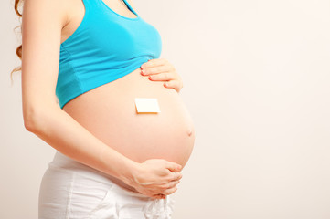 Belly of a young pregnant woman with a sticker on it isolated on white (boy or girl concept)