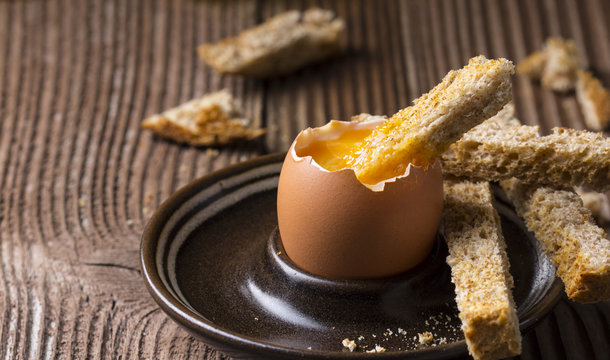 Boiled egg with crispy bread on wooden background