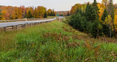 Fall Road Trip. Highway 28 in Michigan's Upper Peninsula crosses the Sturgeon River and winds through the northern forest with autumn foliage.