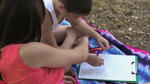 Happy mother and son draw. Mother with her son are drawing pictures in the park