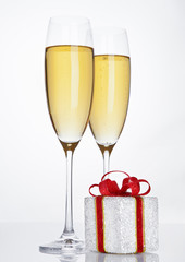 Glasses of sparkling champagne with red gift box