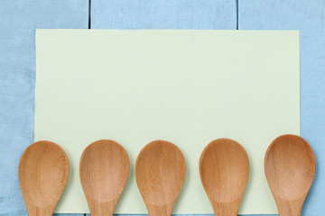 Wooden spoon on green note paper and blue wood table.
