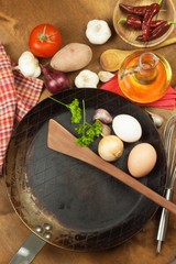 Kitchen iron pan and ingredients to prepare meals. Wooden spoons for cooking. Amenities of home cooking. Sales of kitchen tools.
