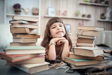 little cheerful girl with stack of books in library;