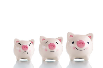 Three white piggy bank with different size small, medium and large and different emotion sad, calm and happy - saving, emotional and investment