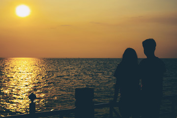 Silhouettes of hugging couple against the sea at sunset.