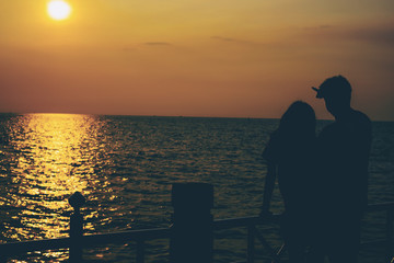Silhouettes of hugging couple against the sea at sunset.