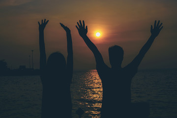 Silhouettes of hugging couple against the sea at sunset.